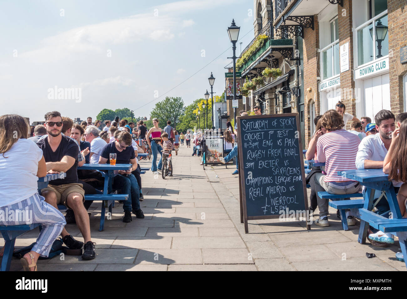 People enjoy the good weather in the beer gardens on Lower Mall in Kensington outside The Rutland Arms pub and Auriol Kensington Rowing Club, Stock Photo