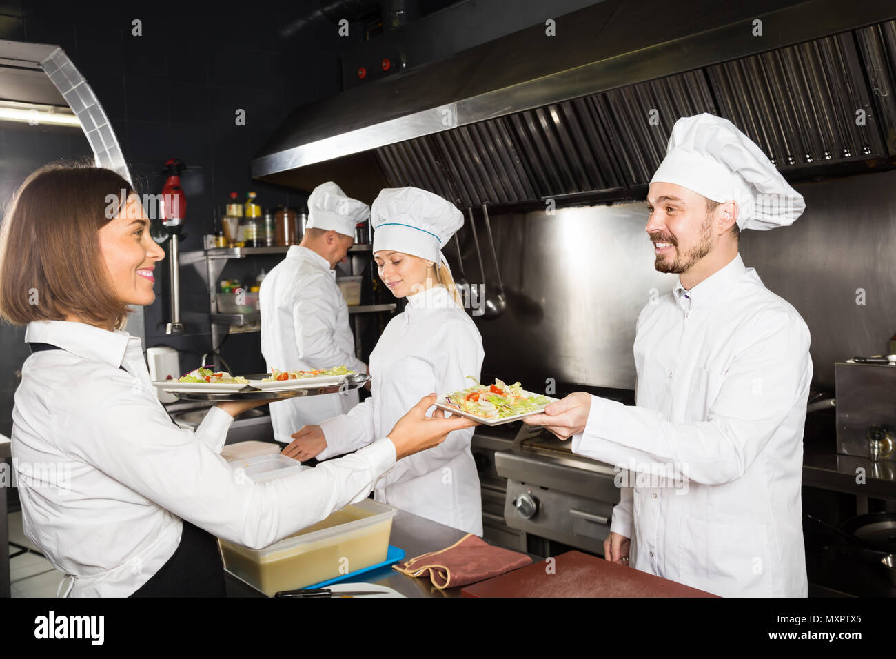 happy female waiter collecting freshly prepared dishes from restaurant’s kitchen Stock Photo Alamy
