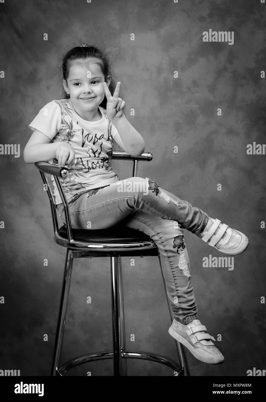 Smiling girl sitting on a chair. Studio shot Stock Photo - Alamy