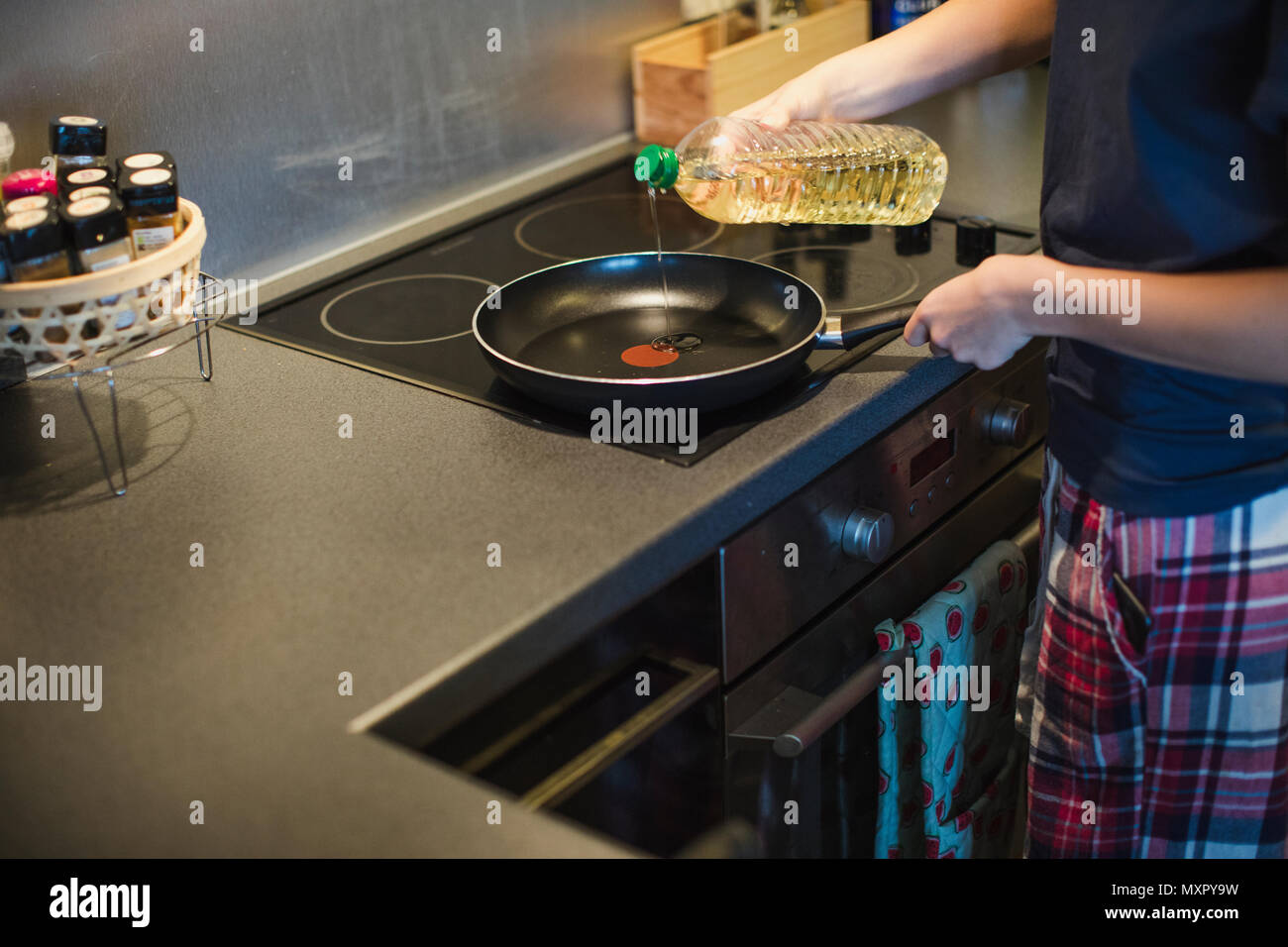 Unrecognisable person pouring oil into a frying pan to make some breakfast. Stock Photo