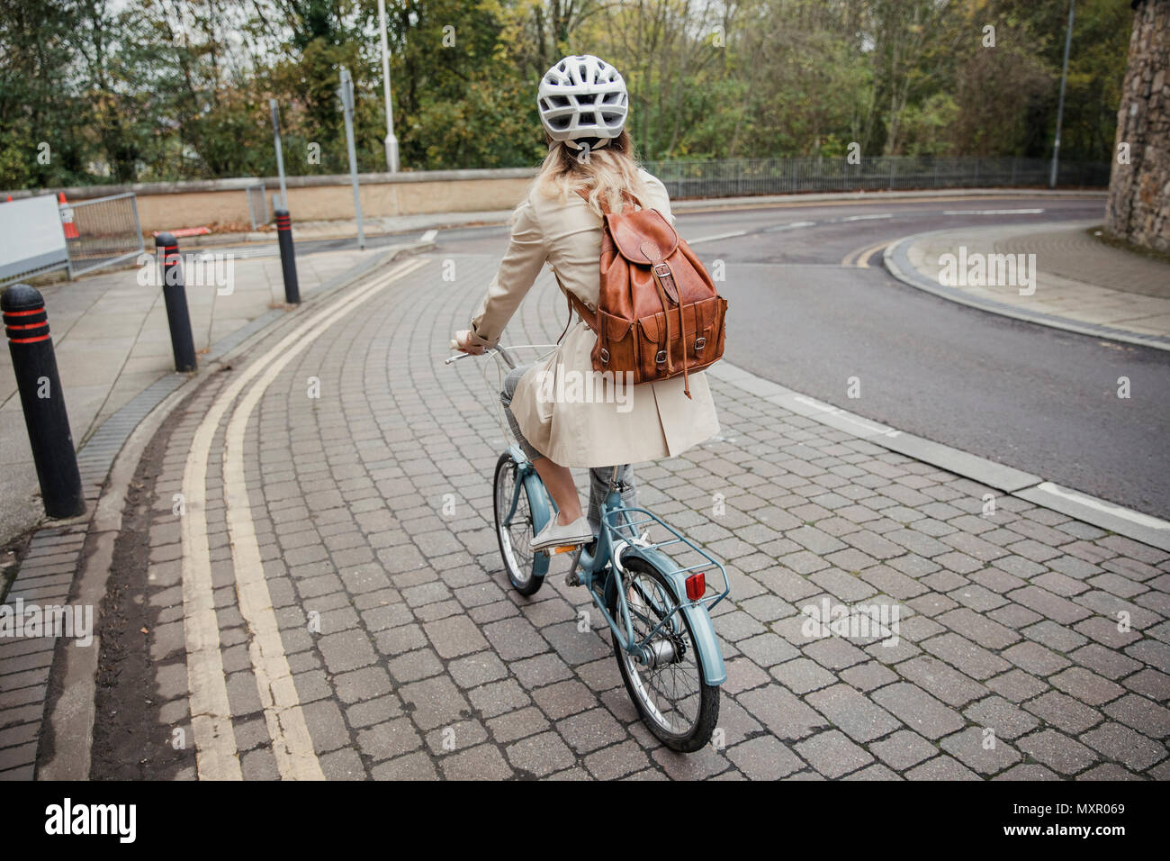 Rear view of an unrecognisable person cycling down the street on the way to work. Stock Photo