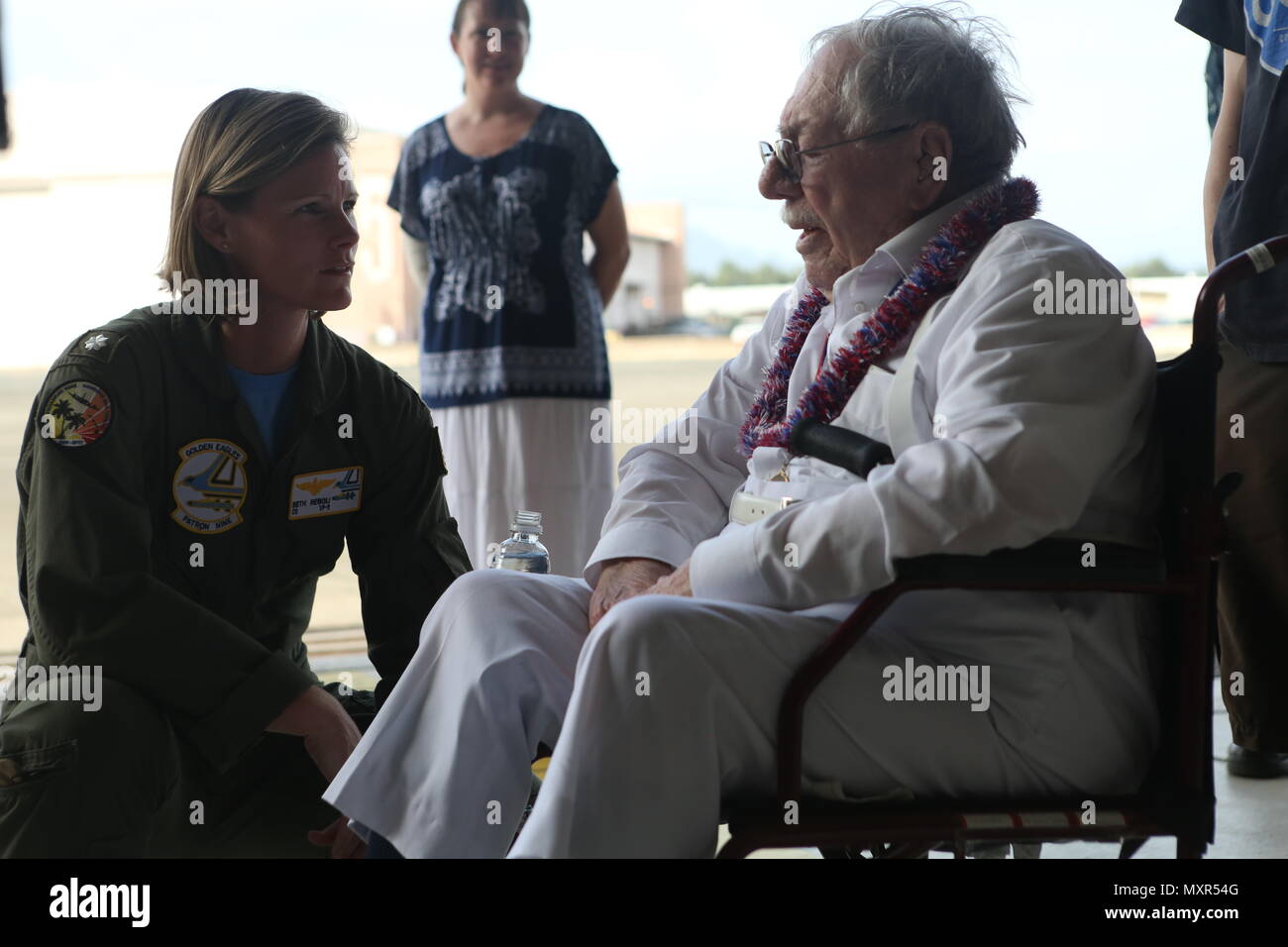 Melvin Heckman, a Pearl Harbor survivor, speaks with Cmdr. Beth Regoli, the commanding officer of Patrol Squadron 9, about his experiences during the attack on Pearl Harbor at Hangar 104 aboard Marine Corps Base Hawaii, December 2, 2016. Heckman is known for rescuing sailors from the USS Arizona during the attack on Pearl Harbor after the ship was attacked by Japanese Zeros. 'I reached out to grab a man's hand to help him up and take him to the island,' said Heckman, a Sheridan, Wyoming, native. 'I got him out of the water and saw that everything below his belly button was missing; he died in  Stock Photo