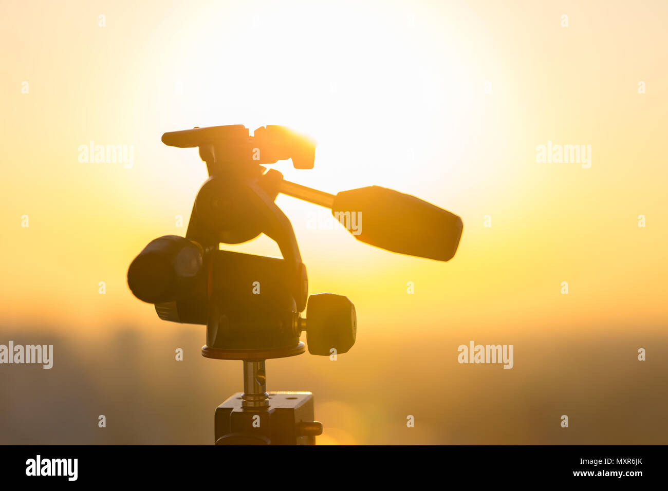 A X-PRO 3 way tripod head mounted on a super clamp with the sun in the background. Stock Photo