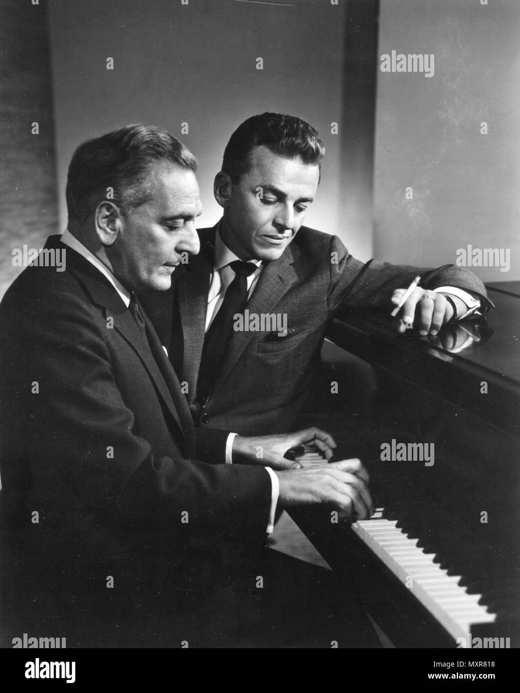 Alan Jay Lerner (with cigarette), and Frederick Loewe work together at the piano on another Broadway musical score. The two collaborated on the Broadway production 'My Fair Lady.' New York, NY, 1960. Stock Photo