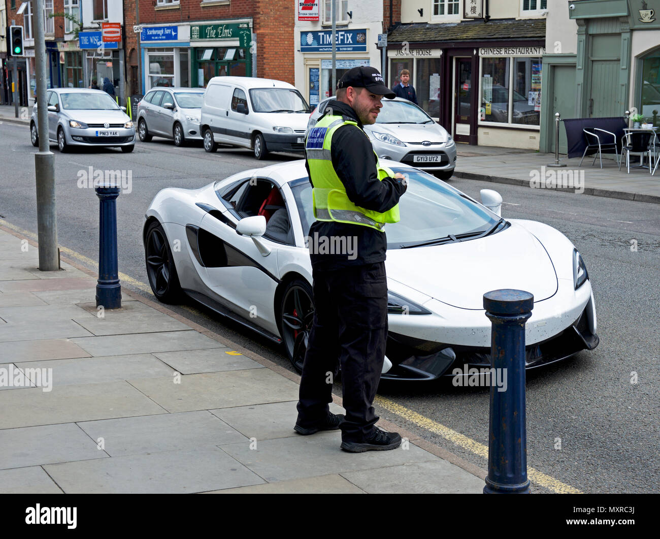 Traffic Warden And Sports Car Parked On Street England UK Stock Photo traffic-warden-and-sports-car-parked-on-street-england-uk-stock-photo