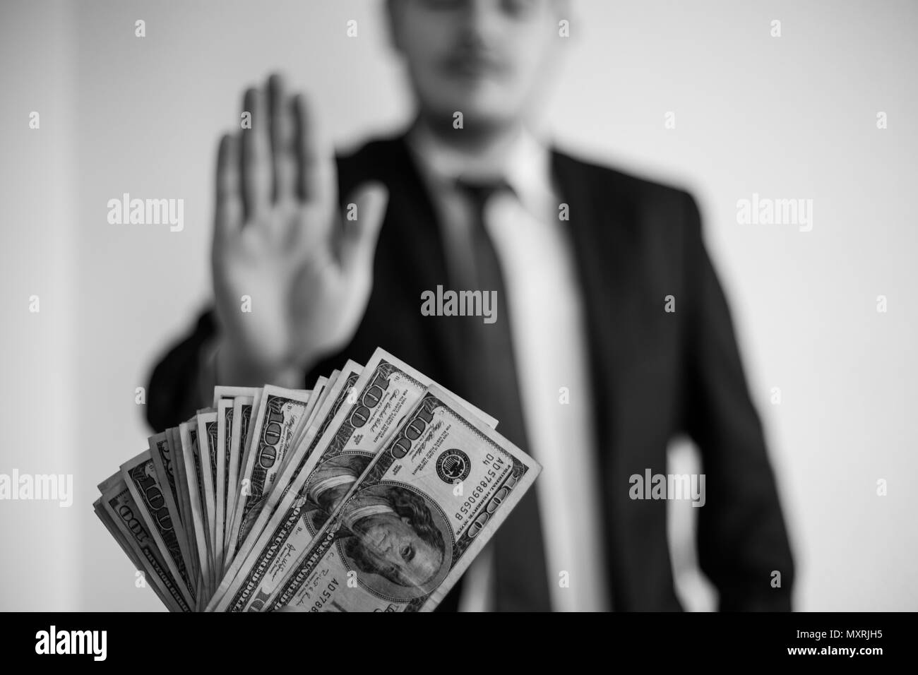 Bribe and corruption, offered cash to a businessman in a suit, does not want to take them, hold upright hands Stock Photo