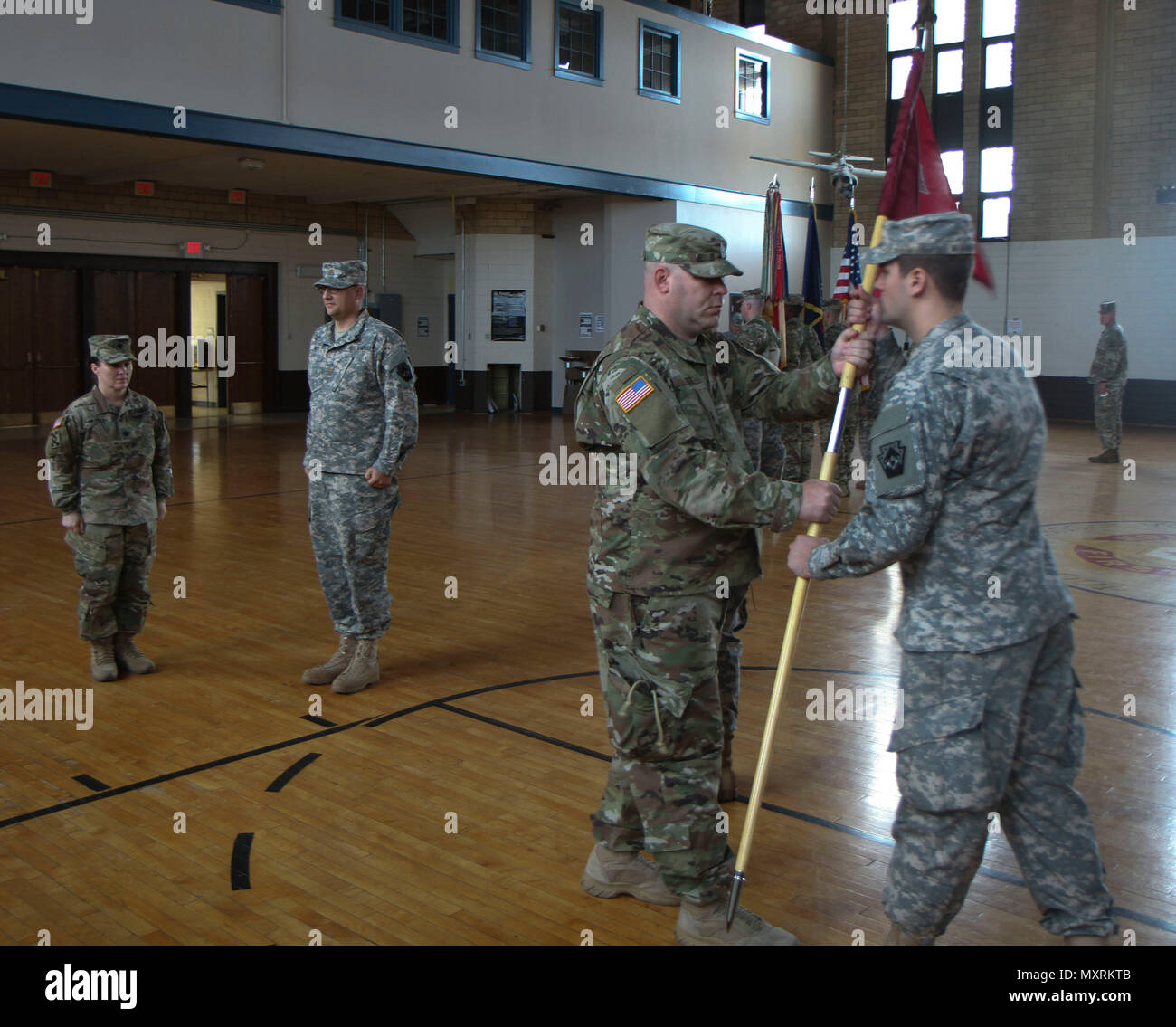 1st Sgt. Chad Schell (second from right) of the 108th Medical Company presents the newly unfurled colors of his unit to Spc. Bradley Wanamaker (right), a medic, during the activation ceremony for the 108th November 6 in Allentown, Pa. Lt. Col. Laura McHugh (left), commander of the 213th RSG and Maj. Daniel S. Wise, commander of the 108th Medical Company conferred their trust on the new unit to provide area medical support. (U.S. Army National Guard photo by Sgt. Zane Craig) Stock Photo
