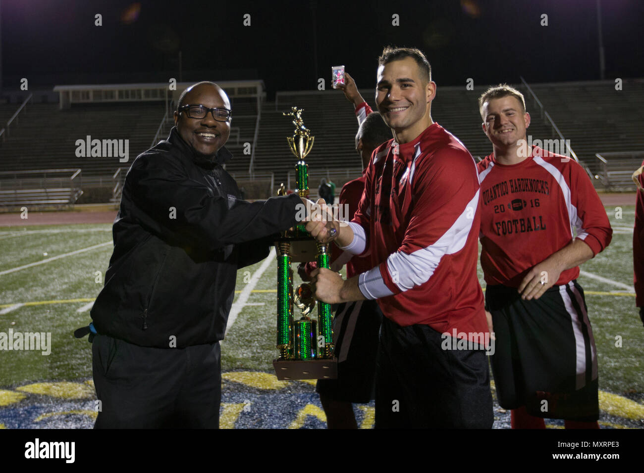 Joel Hines, left, director of the intramural sports program, Marine Corps Base Quantico (MCBQ), presents the first place trophy to the Base Motor Transport team during the Marine Corps Community Services Intramural Flag Football Championship Tournament at Butler Stadium, MCBQ, Va., Dec. 1, 2016. Marines from different units volunteer to compete in an intermural flag football league. (U.S. Marine Corps photo by Lance Cpl. Cristian L. Ricardo) Stock Photo
