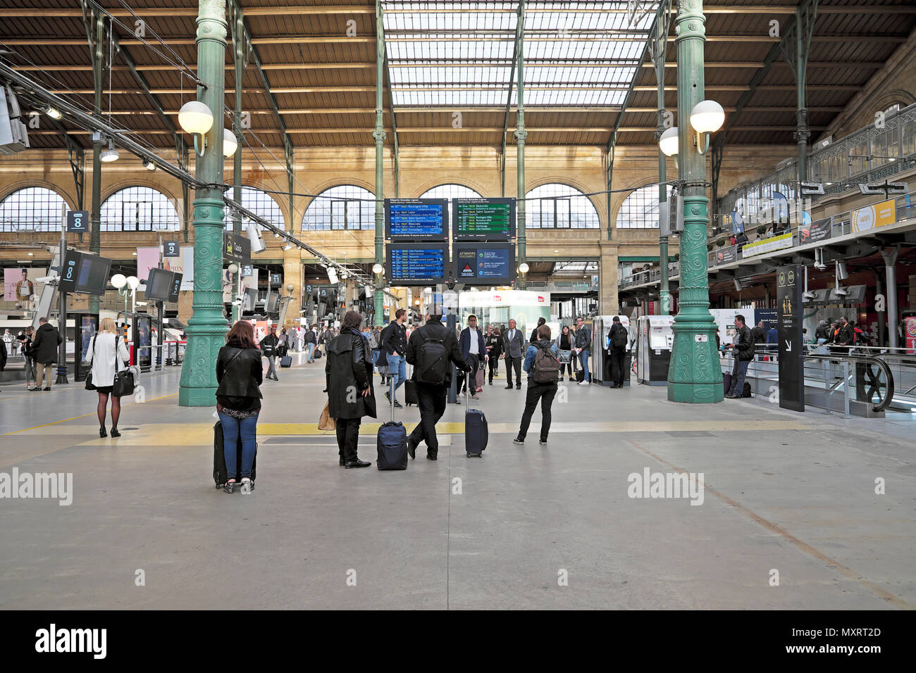 Interior view of passengers with luggage looking at arrival and