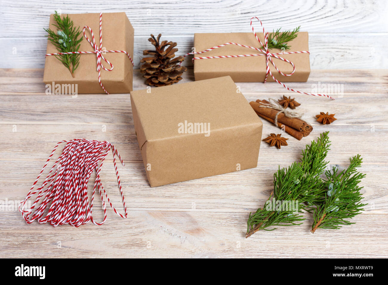 Creative hobby. Gift wrapping. Packaging modern christmas present boxes in stylish gray paper with satin red ribbon. Top view wood table with fir tree Stock Photo