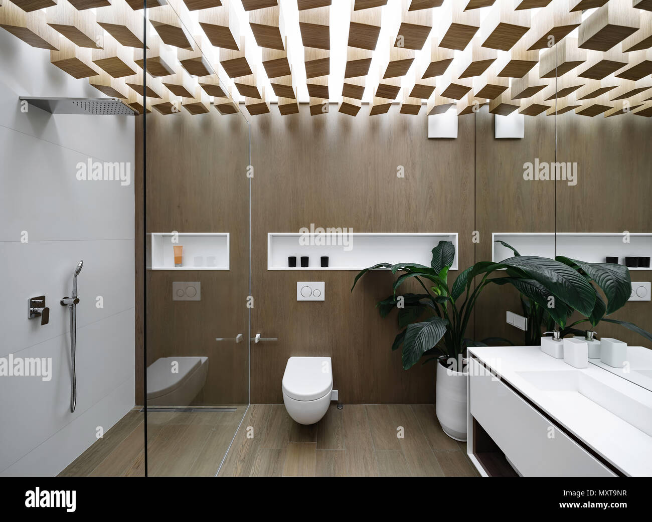 Afslut fusion Præfiks Luminous modern bathroom with design ceiling and wooden walls. There is a  glass shower cabin with light tiled wall, white toilet, sink with a mirror  Stock Photo - Alamy