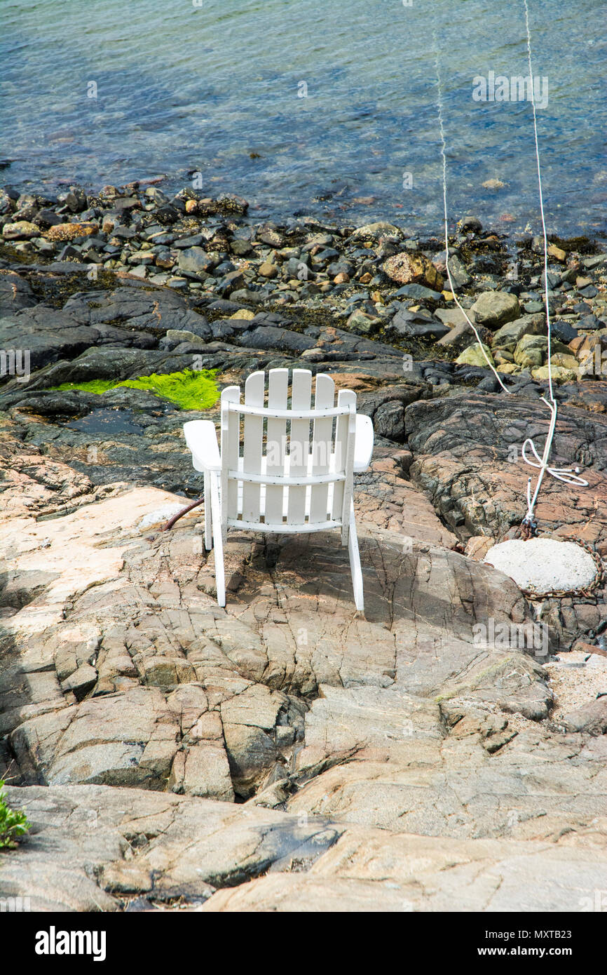 Adirondack chair placed on smooth rock for enjoyment of viewing the sea, Stock Photo