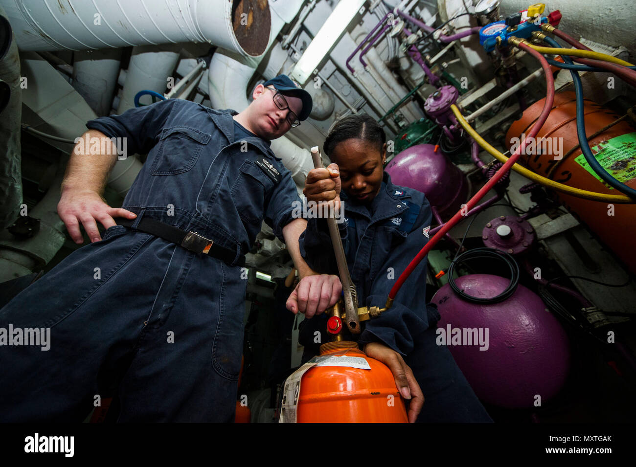 161205-N-IV489-048 ATLANTIC OCEAN (Dec. 5, 2016) Petty Officer 3rd Class Learneice Ussery, right, from Macon, Georgia, uses a crescent wrench to charge a refrigerant to the reefer system aboard the aircraft carrier USS George Washington (CVN 73). George Washington, homeported in Norfolk, is underway conducting carrier qualifications in the Atlantic Ocean. (U.S. Navy Photo by Seaman Oscar Albert Moreno Jr.) Stock Photo