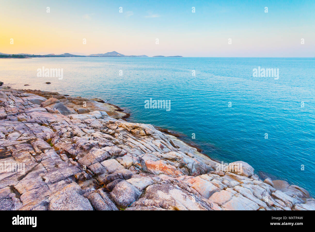 The pile of the boulders next to the calm blue ocean. The kingdom of Thailand. Ideal background in beige, blue shades for the different kinds of the marine illustrations and collages. Stock Photo