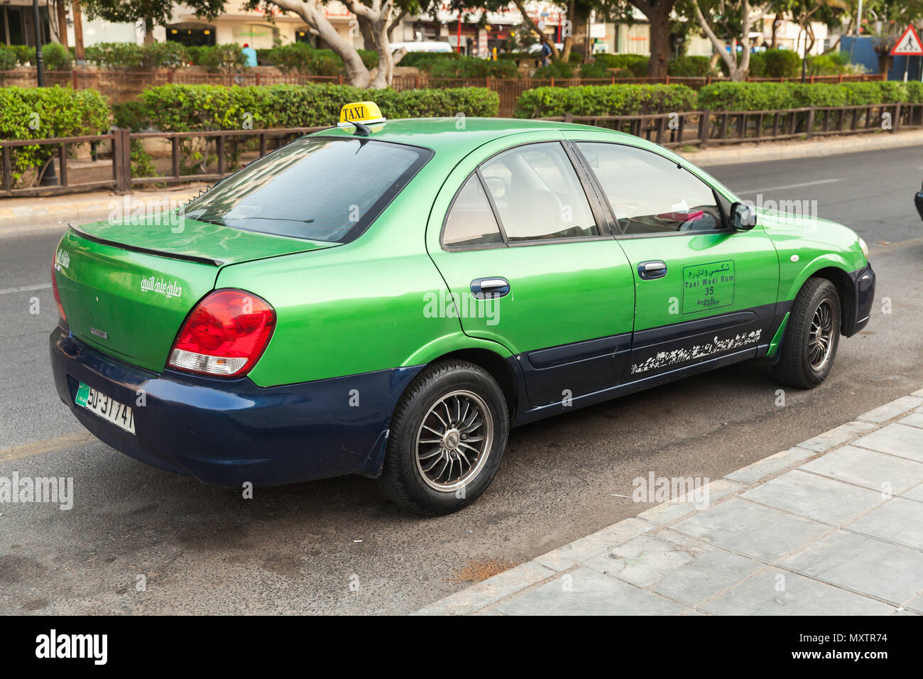Aqaba, Jordan - May 18, 2018: Green taxi car stands parked on a street side in Aqaba city, rear view Stock Photo