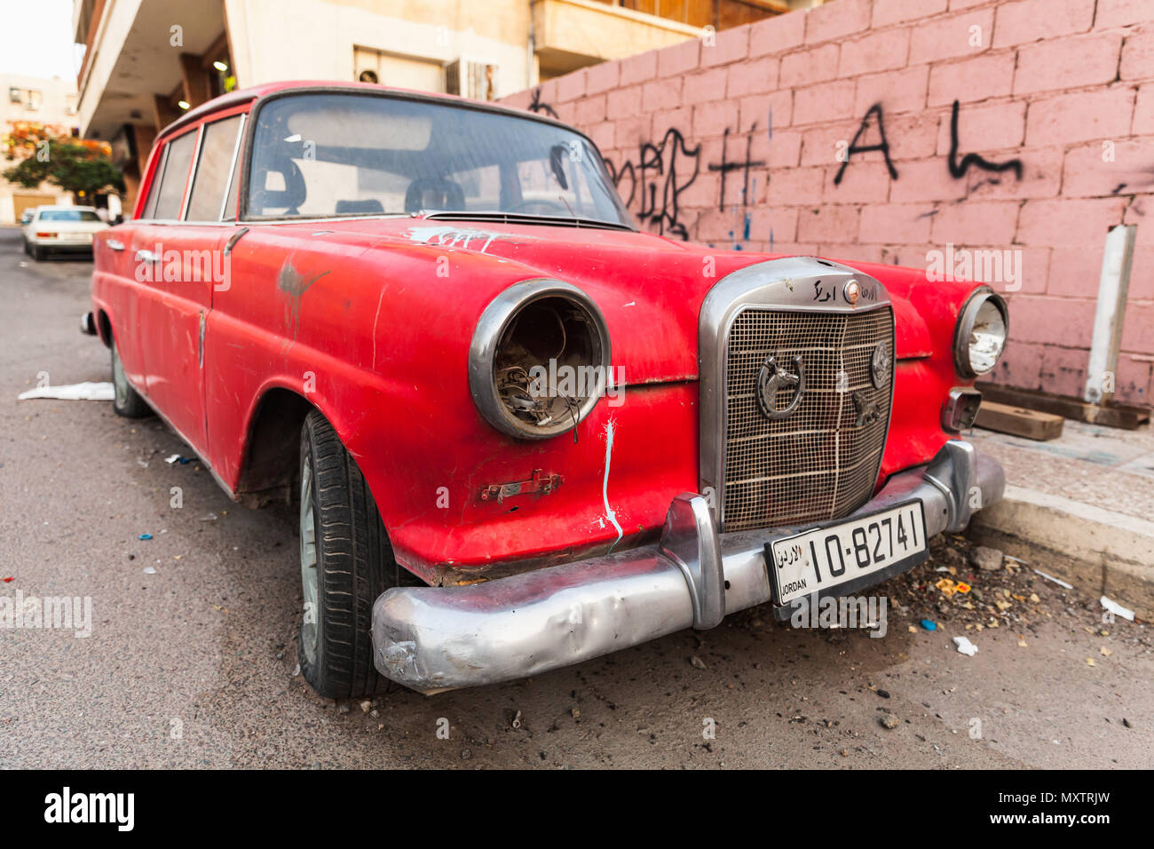 Aqaba, Jordan - May 18, 2018: Red abandoned Mercedes-Benz W110 190, midsize automobile stands on a roadside in Aqaba city, close-up photo Stock Photo