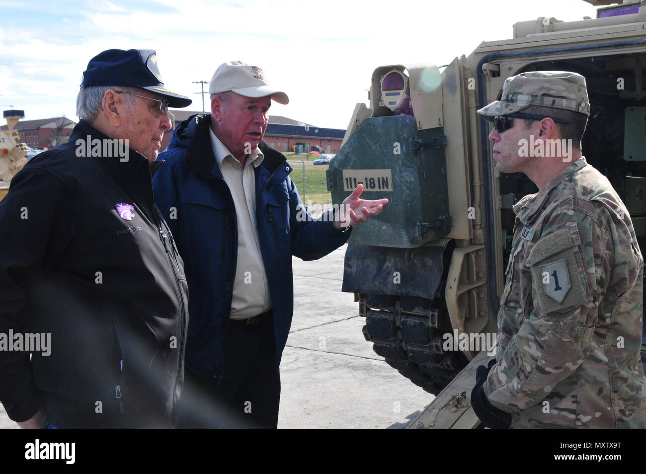 Staff Sgt. Juan Cruz, a section sergeant assigned to Company B, 1st Combined Arms Battalion, 28th Infantry Regiment, 2nd Armored Brigade Combat Team, 1st Infantry Division, speaks with retired Col. Edwin W. Chamberlain III and Jim Sharp about the M2 Bradley fighting vehicle Dec. 1 during a visit in the “Vanguard” battalion motor pool on Fort Riley. Chamberlain, who is the 18th Inf. Regt. honorary colonel, and Sharp were among the five veterans invited by the Vanguard battalion to tour the area of operations and attend the unit’s reunion ball. (Sgt. Takita Lawery, 19th Public Affairs Detachment Stock Photo