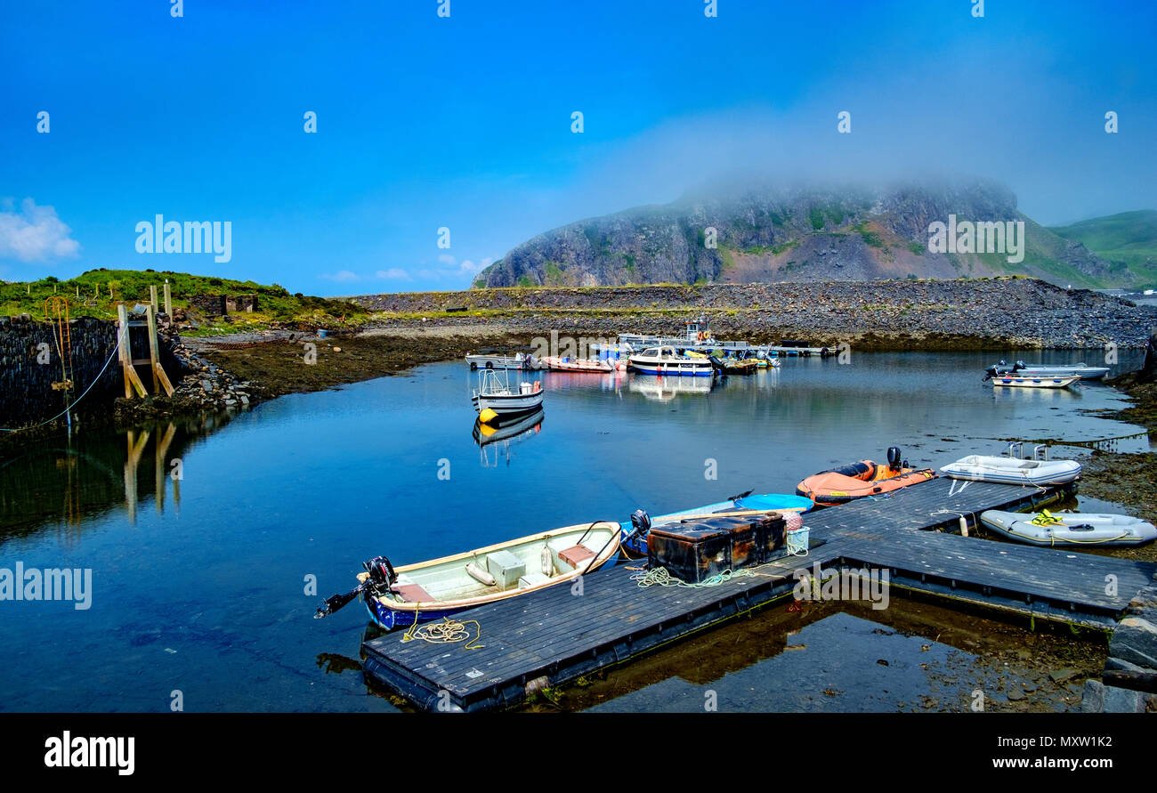 The tiny harbour on Easdale Island with Seil Island shrouded in low cloud in the background.  Easdale Island, the smallest permanently-inhabited islan Stock Photo
