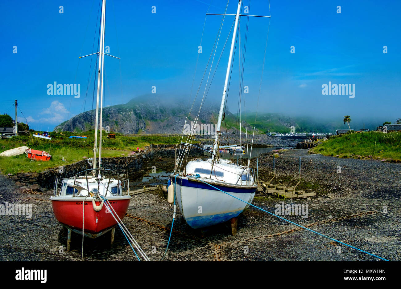 Yauchts tied up beside the tiny harbour on Easdale Island with Seil Island shrouded in low cloud in the background.  Easdale Island, the smallest perm Stock Photo