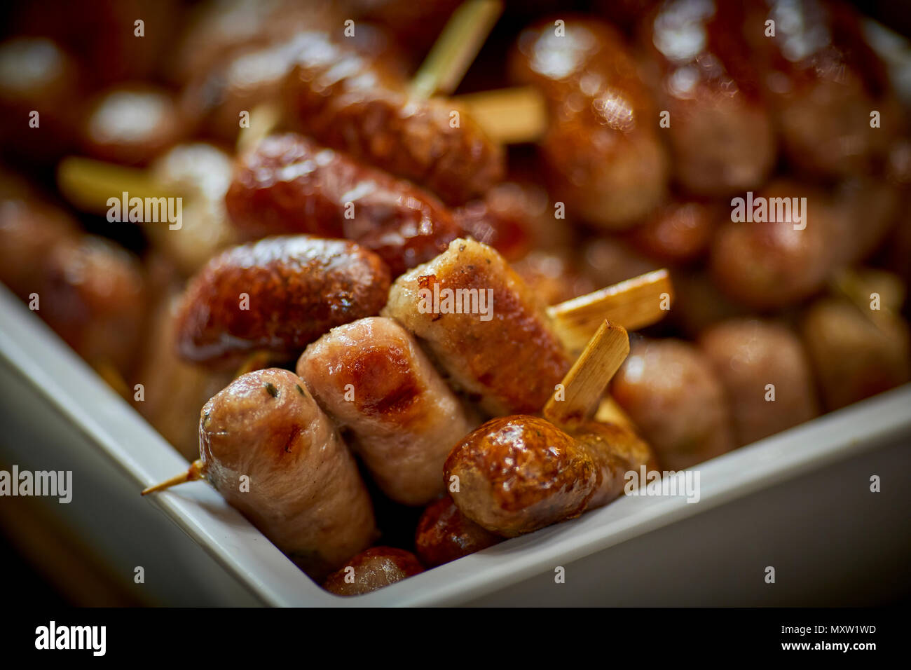 small pork sausages in tray on wooden skewers Stock Photo Alamy