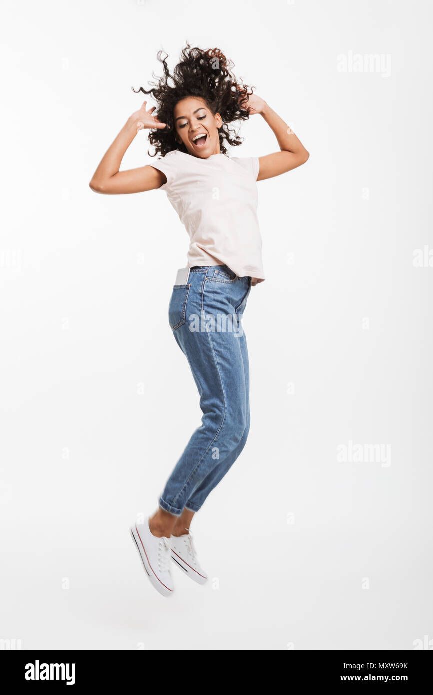 Full length image of attractive african american woman with brown curly hair wearing jeans and t-shirt posing with pleasant smile isolated over white  Stock Photo