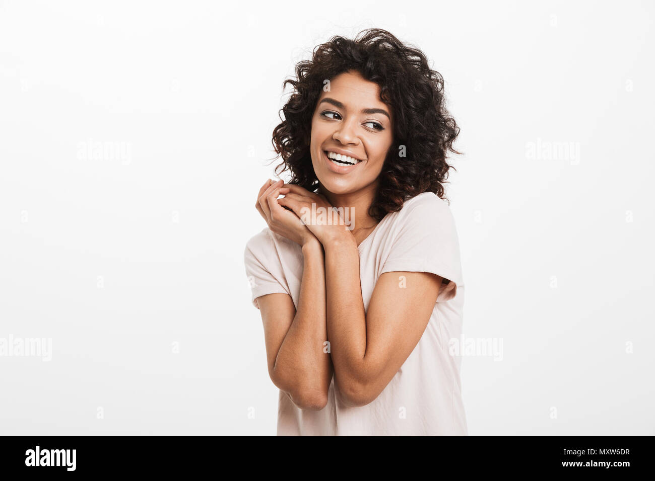 Portrait of beautiful american woman wearing jeans and t-shirt keeping arms together at chest and smiling isolated over white background Stock Photo