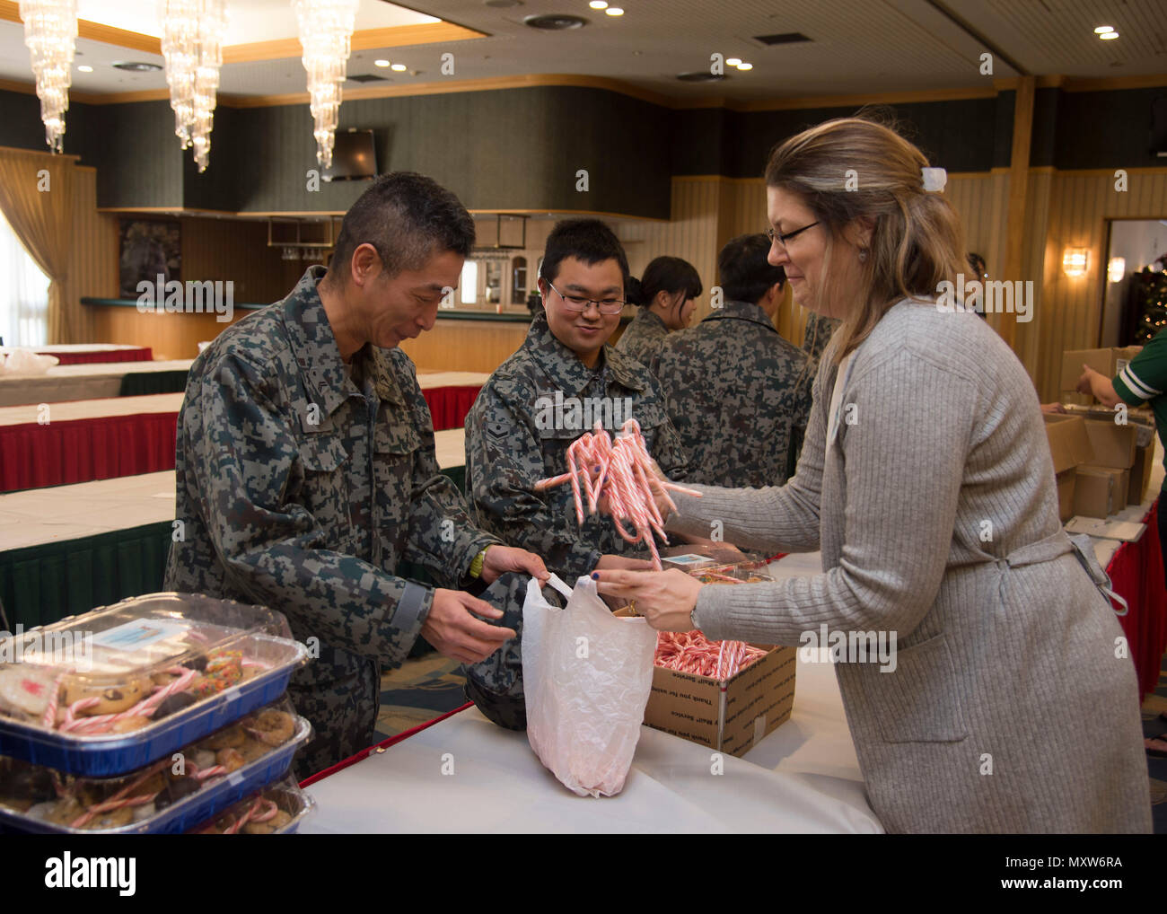 Japan Air-Self Defense Force members receive candy canes from Karri Frizzell, the Cookie Caper committee leader, during the annual event at Misawa Air Base, Japan, Dec. 7, 2016. The Cookie Caper leads also included JASDF members because they are also away from their families during the holidays. Additionally, the volunteers provided a CD of holiday music as an extra gift to the JASDF members. (U.S. Air Force photo by Senior Airman Deana Heitzman) Stock Photo