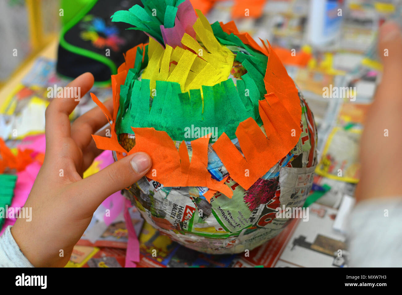 Children hands are making a pinata with colorful paper and glue. Stock Photo