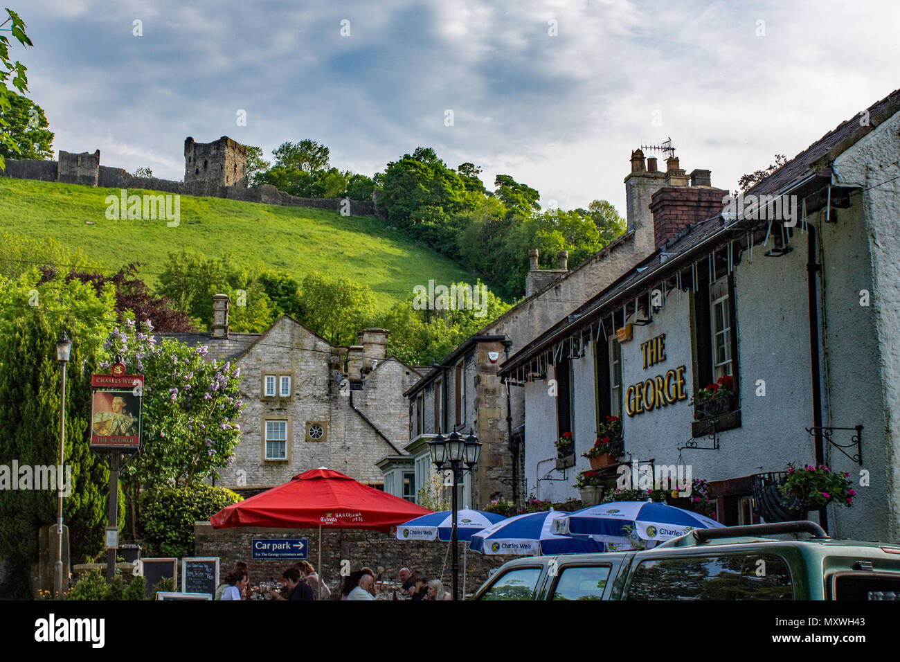 The George Inn, Castleton in the Peak District is overlooked by the ruin of Peveril Castle Stock Photo