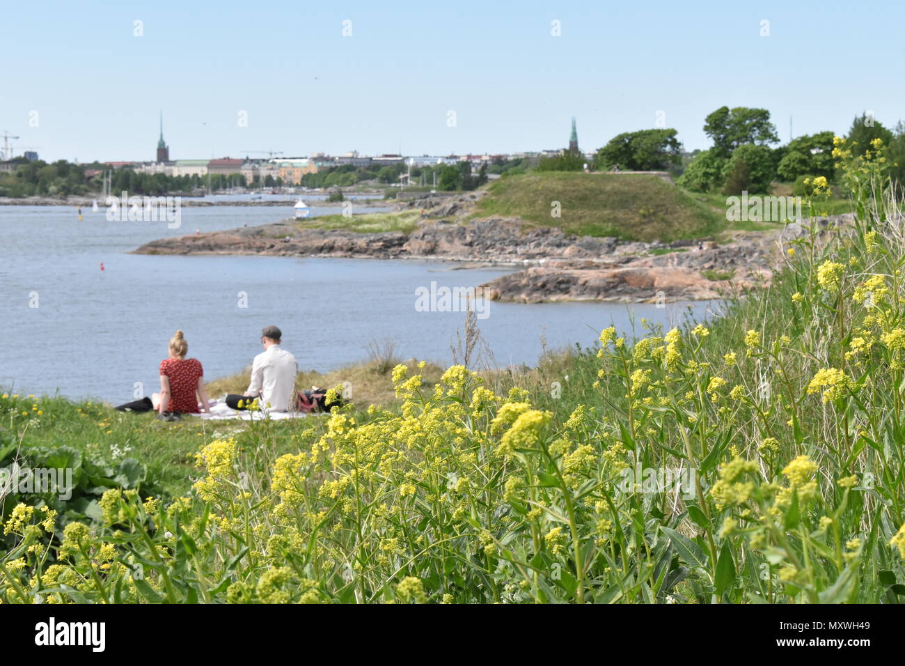 Young Finnish couple on a cosy Sunday romantic beach picnic with a blanket. Suomenlinna. Stock Photo
