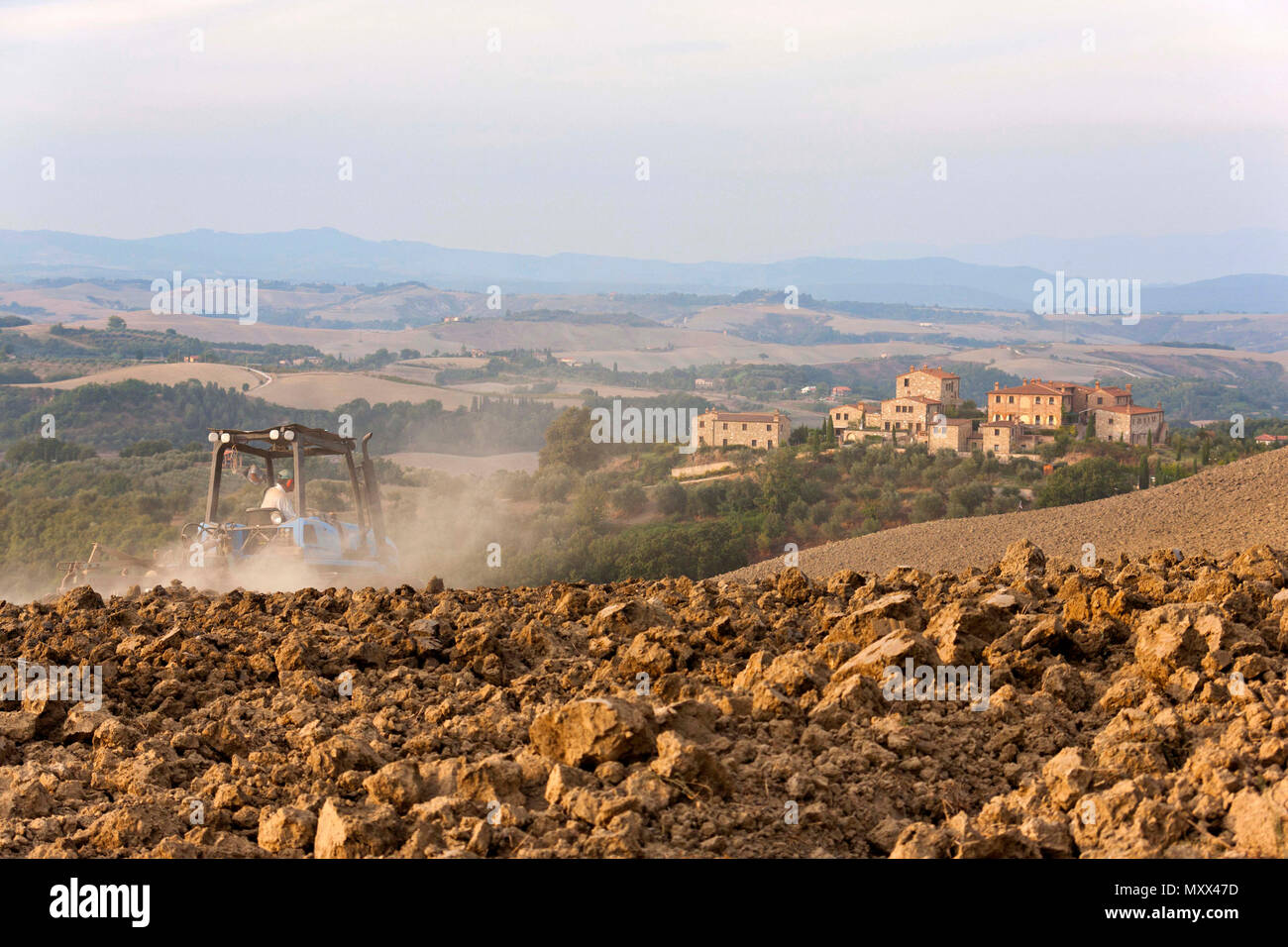 Italian farmer ploughing field with tractor, Crete, Province of Siena, Tuscany, Italy Stock Photo