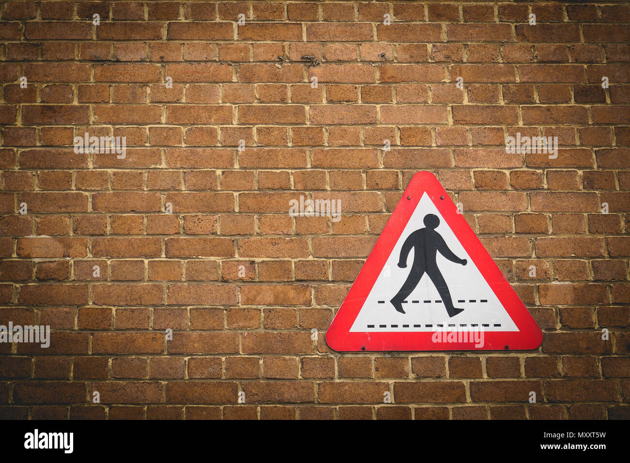 Vintage pedestrian crossing sign on a brick wall background. Landscape format. Stock Photo
