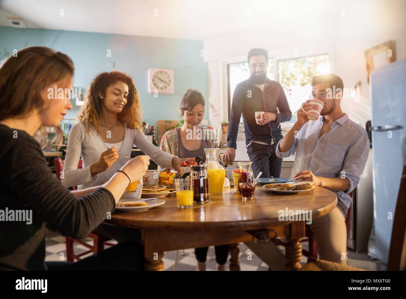 bunch of multi-ethnic friends gathered around a table for breakf Stock Photo