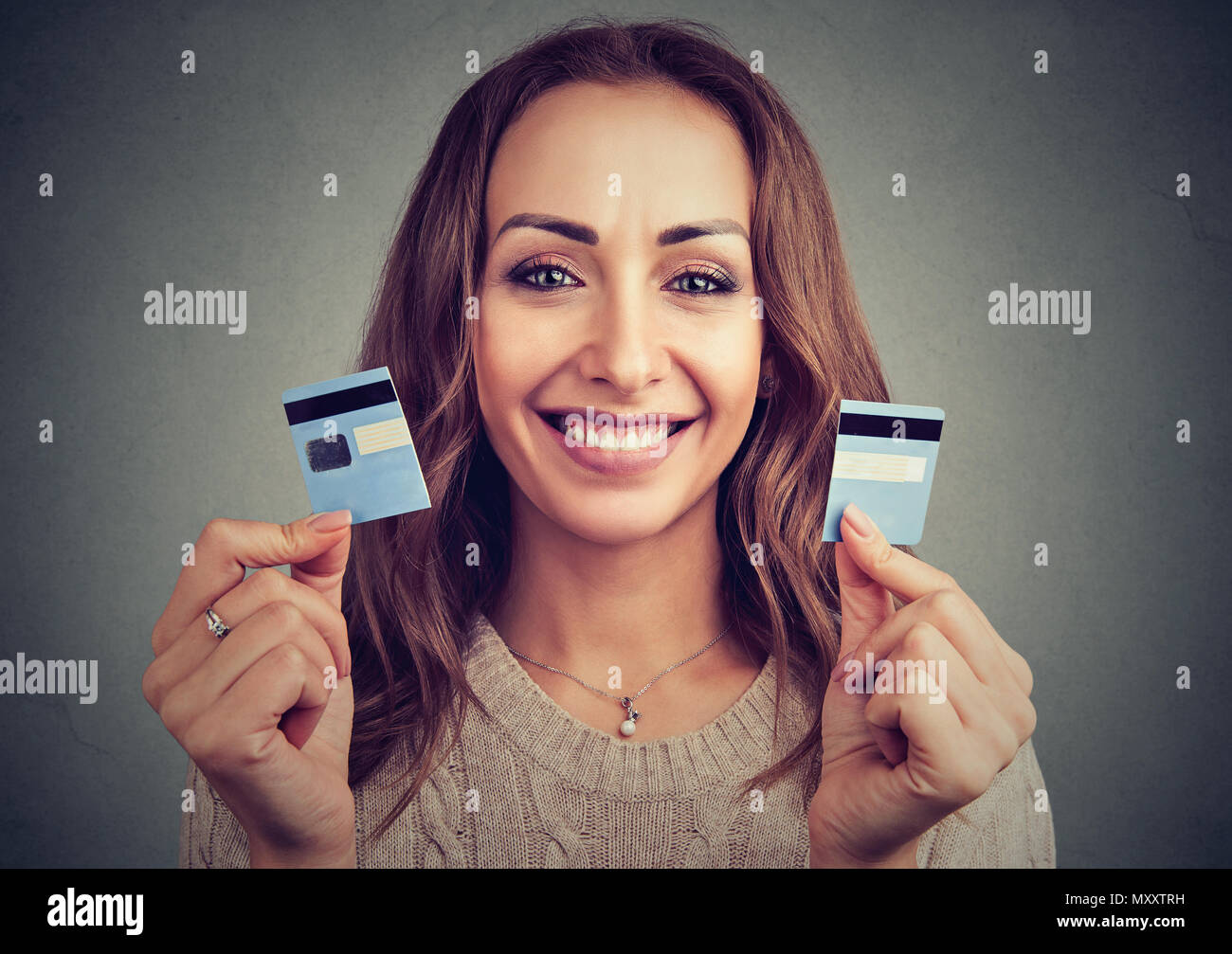 Beautiful young woman holding credit card cut into halves and looking happy debt payout Stock Photo