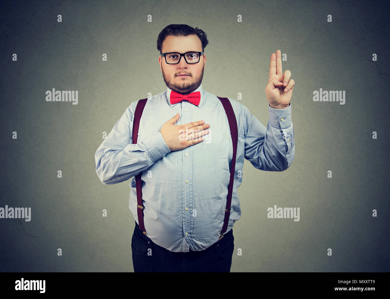 Confident serious man in formal outfit holding hand on chest and making promise looking at camera Stock Photo