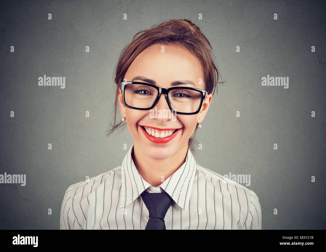 Young girl in glasses and formal outfit wearing red lipstick and smiling excitedly at camera Stock Photo