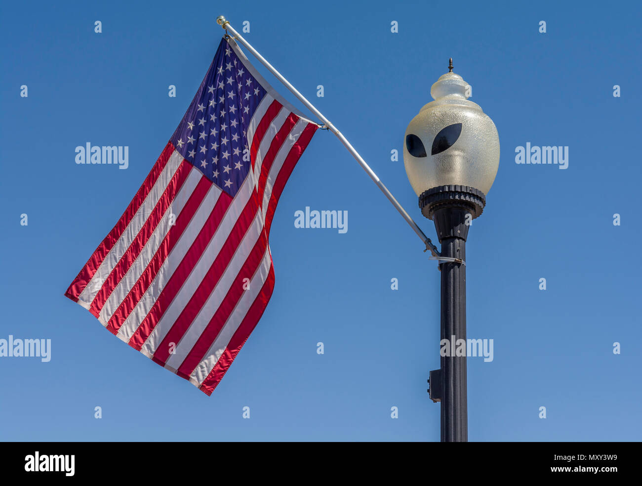 Roswell New Mexico, USA alien streetlight and American Flag against blue sky. Stock Photo