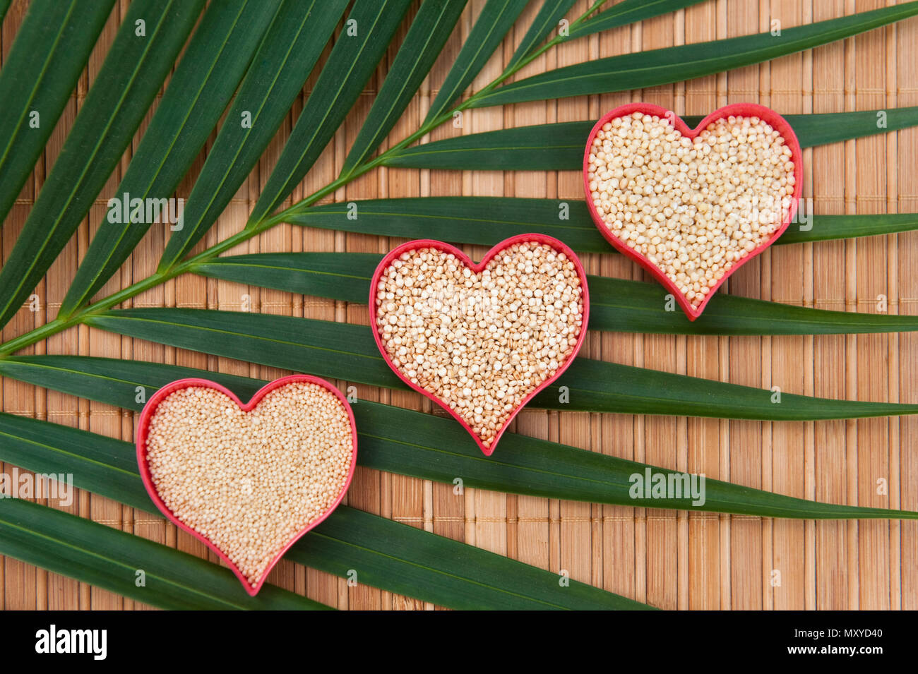 Three hearts filled with amaranth, millet and quinoa on palm leaf Stock Photo