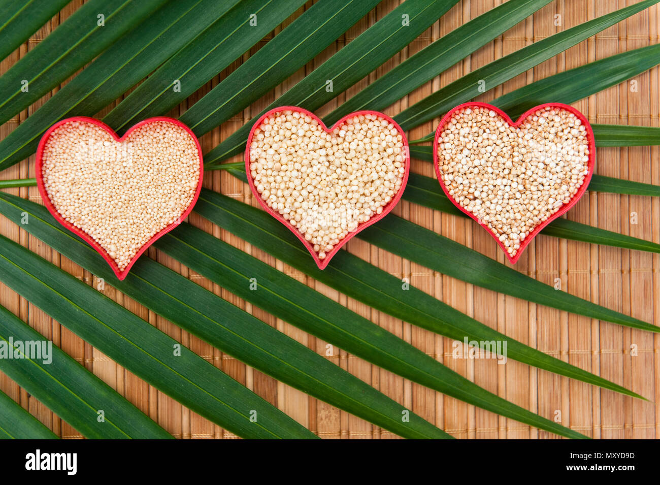 Hearts filled with healthy amaranth, millet and quinoa on a palm leaf