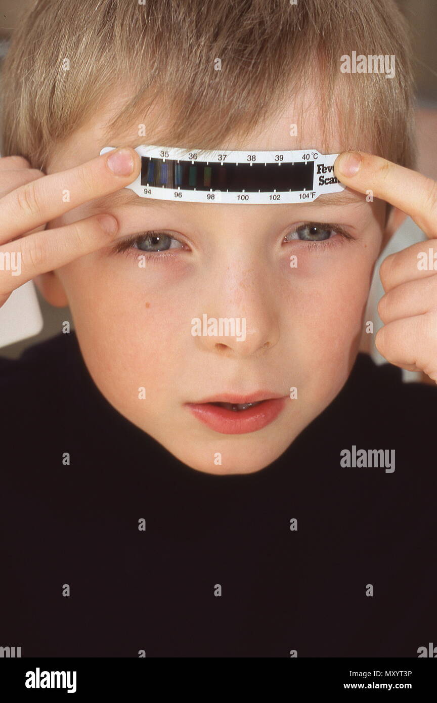 Young boy taking his temperature with a forehead thermometer Stock Photo Alamy