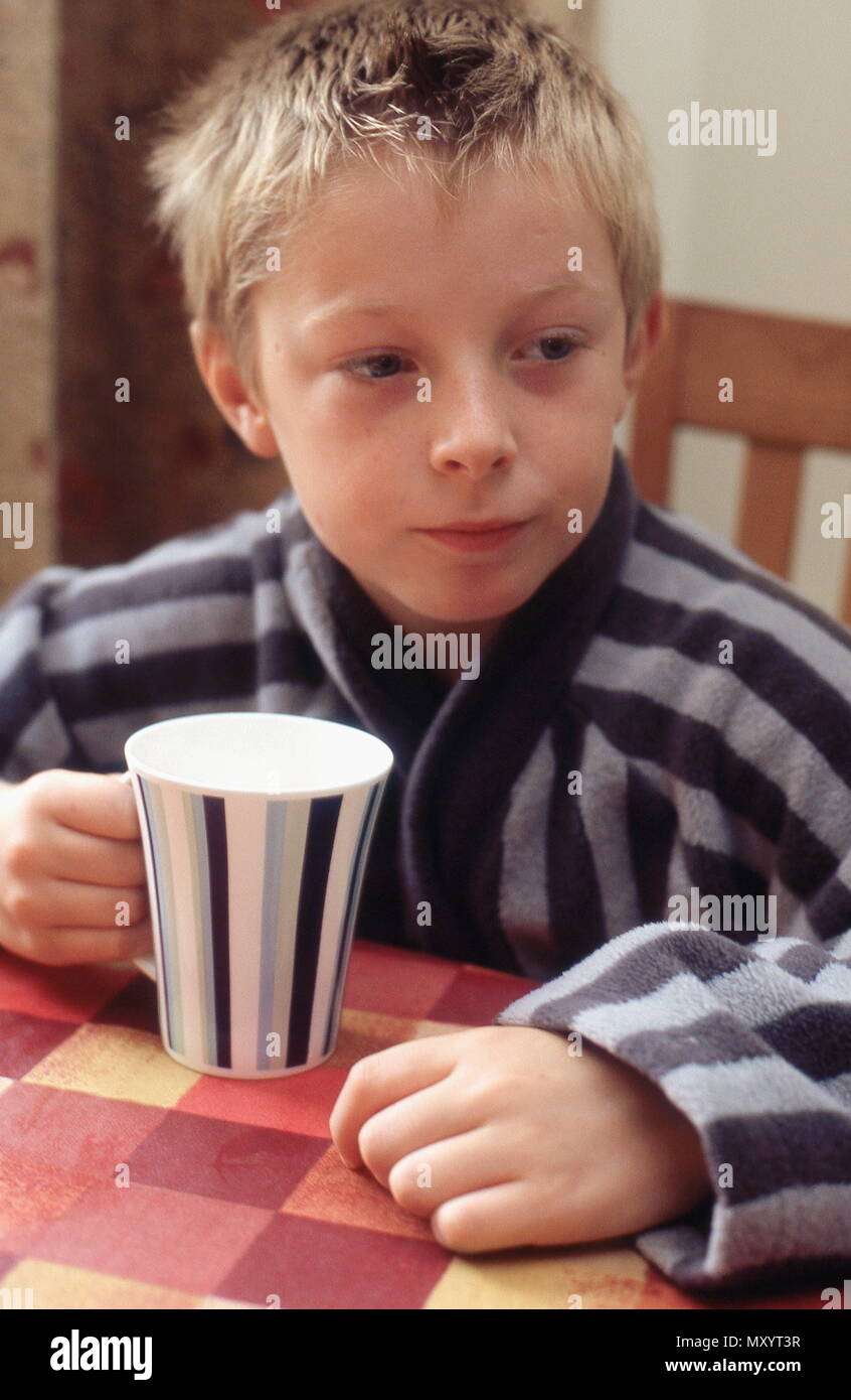 Young boy in his dressing gown enjoying a drink Stock Photo Alamy