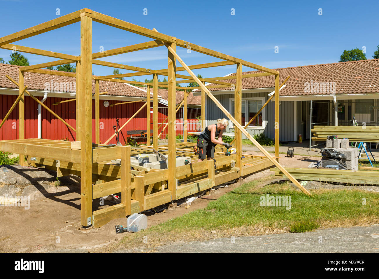 Joiners working outdoors on erecting a large patio with pergola and round firepit Stock Photo