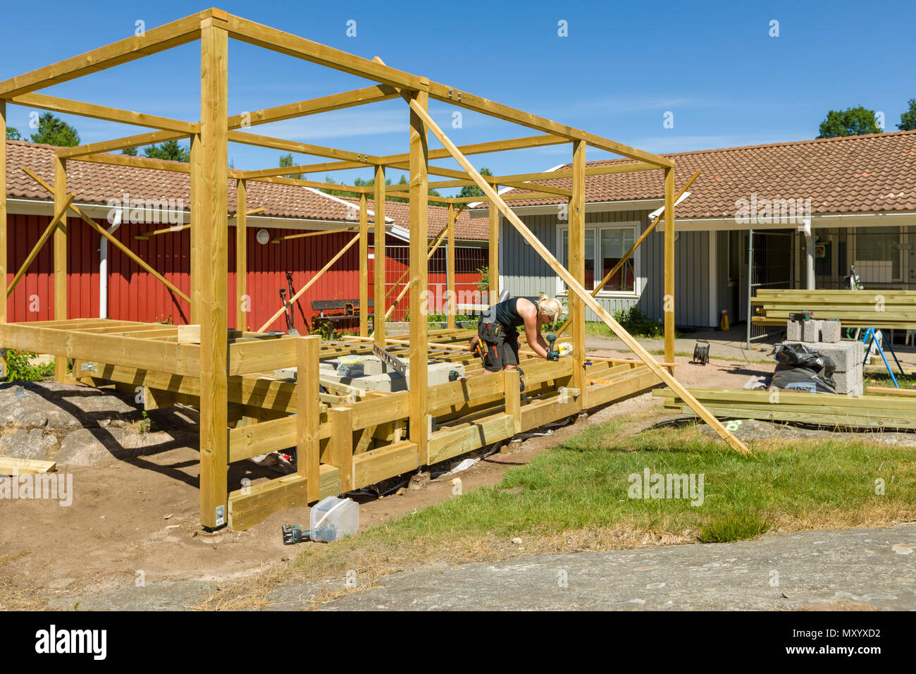Joiners working outdoors on erecting a large patio with pergola and round firepit Stock Photo
