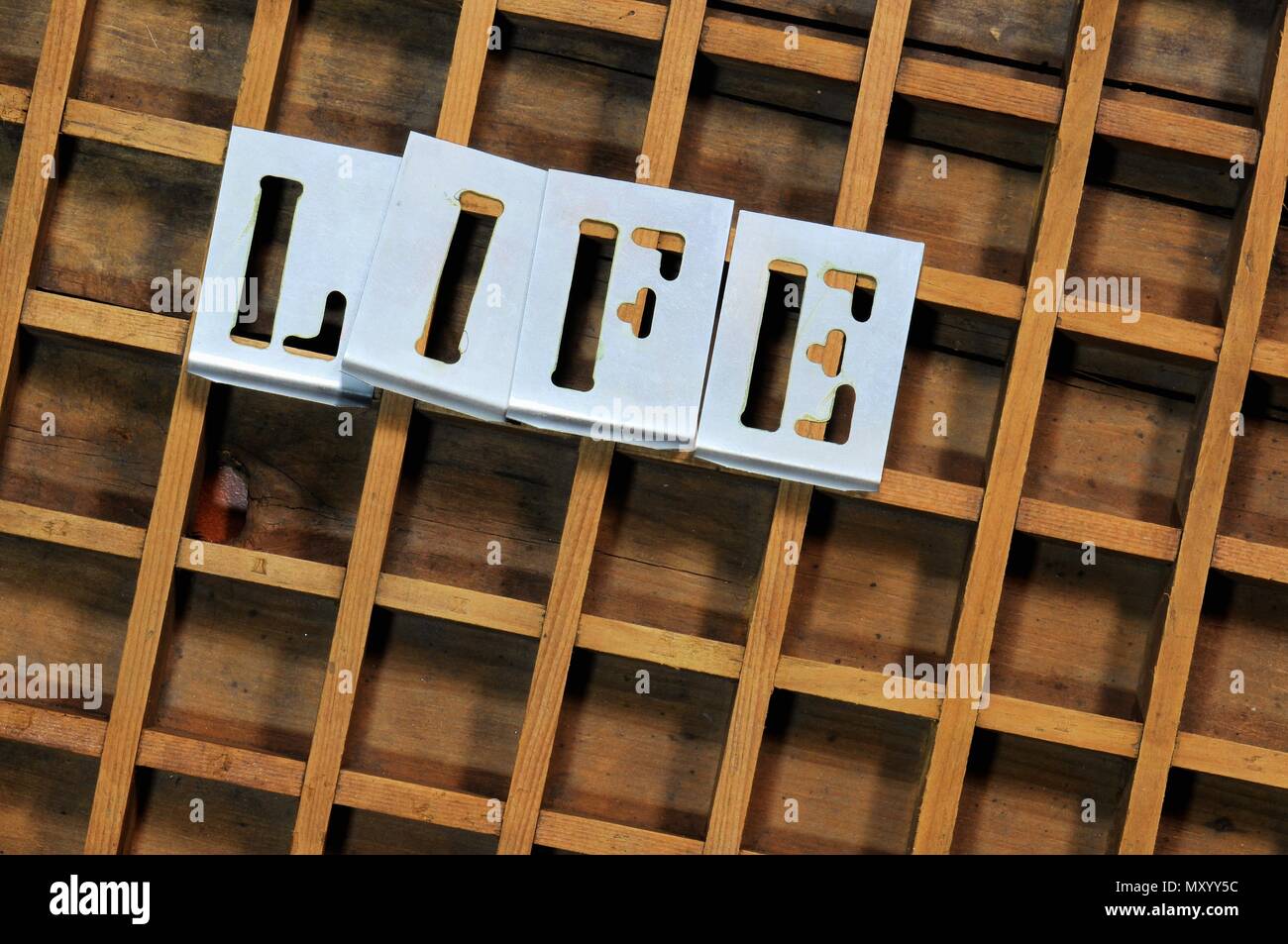 Word 'LIFE' with stencils on old typefaces wooden container. Stock Photo