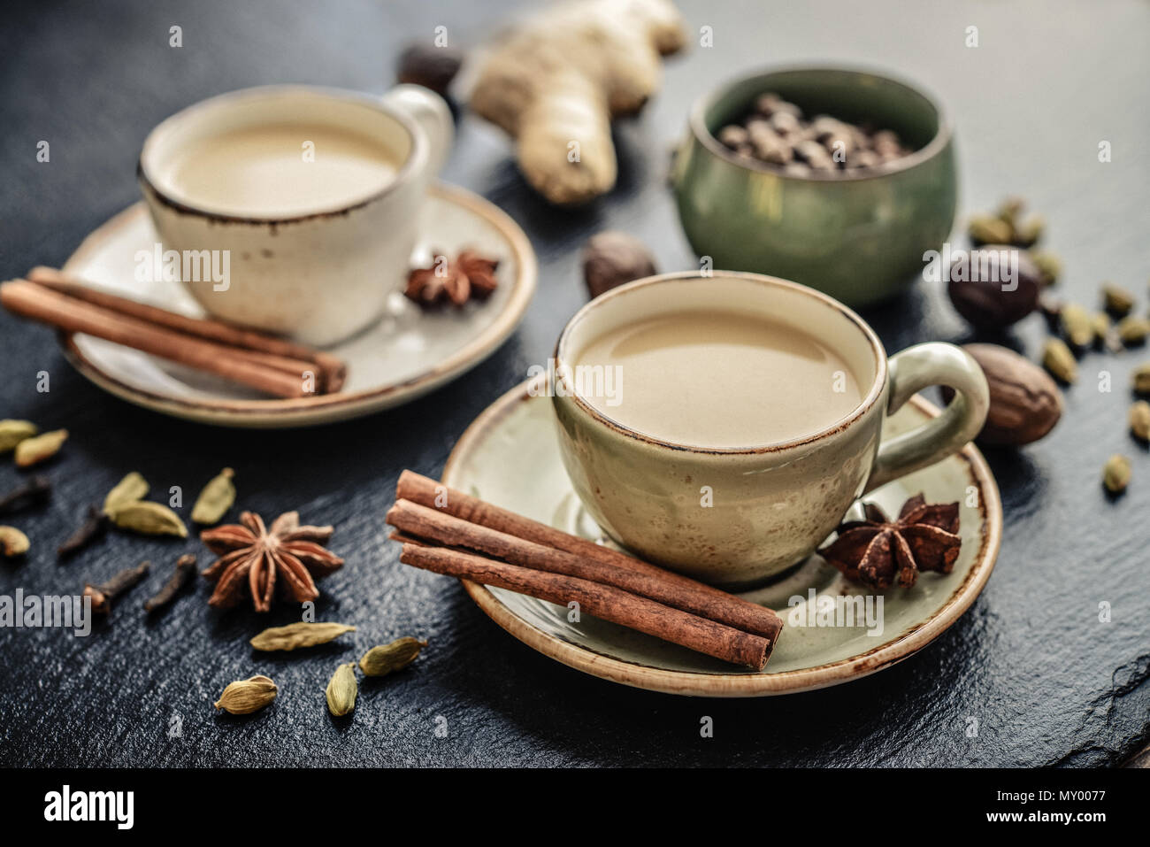 Traditional indian drink - masala chai tea (milk tea) with spices on black slate  background Stock Photo