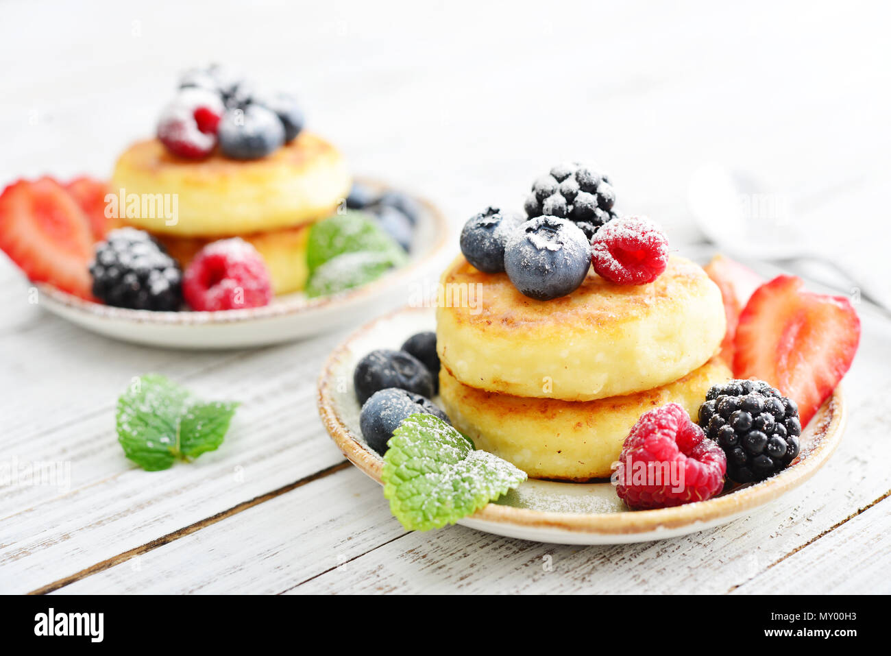 Cottage cheese pancakes, syrniki, curd fritters with fresh berries on wooden background Stock Photo