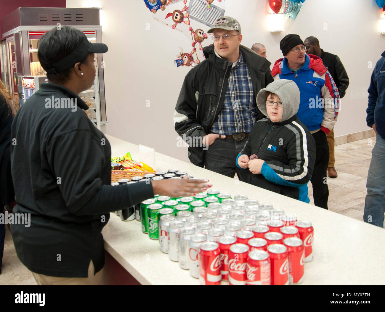 Master Sgt. Robert Bedwell (third from left), Air National Guard Bureau Command Post training and standardization manager, and his son, Connor, place an order with Shavown Brown, movie theater attendant, at the movie theater concession stand at Joint Base Andrews, Md., Dec. 16, 2016. The theater will close again late January 2017 so new seats can be installed before the grand opening the following month. (U.S. Air Force photo by Staff Sgt. Joe Yanik) Stock Photo