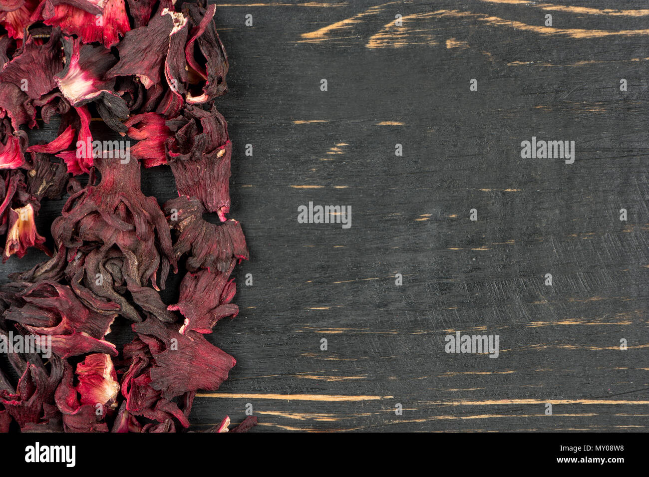 Scattered dry hibiscus tea on an empty wooden background, top view Stock Photo