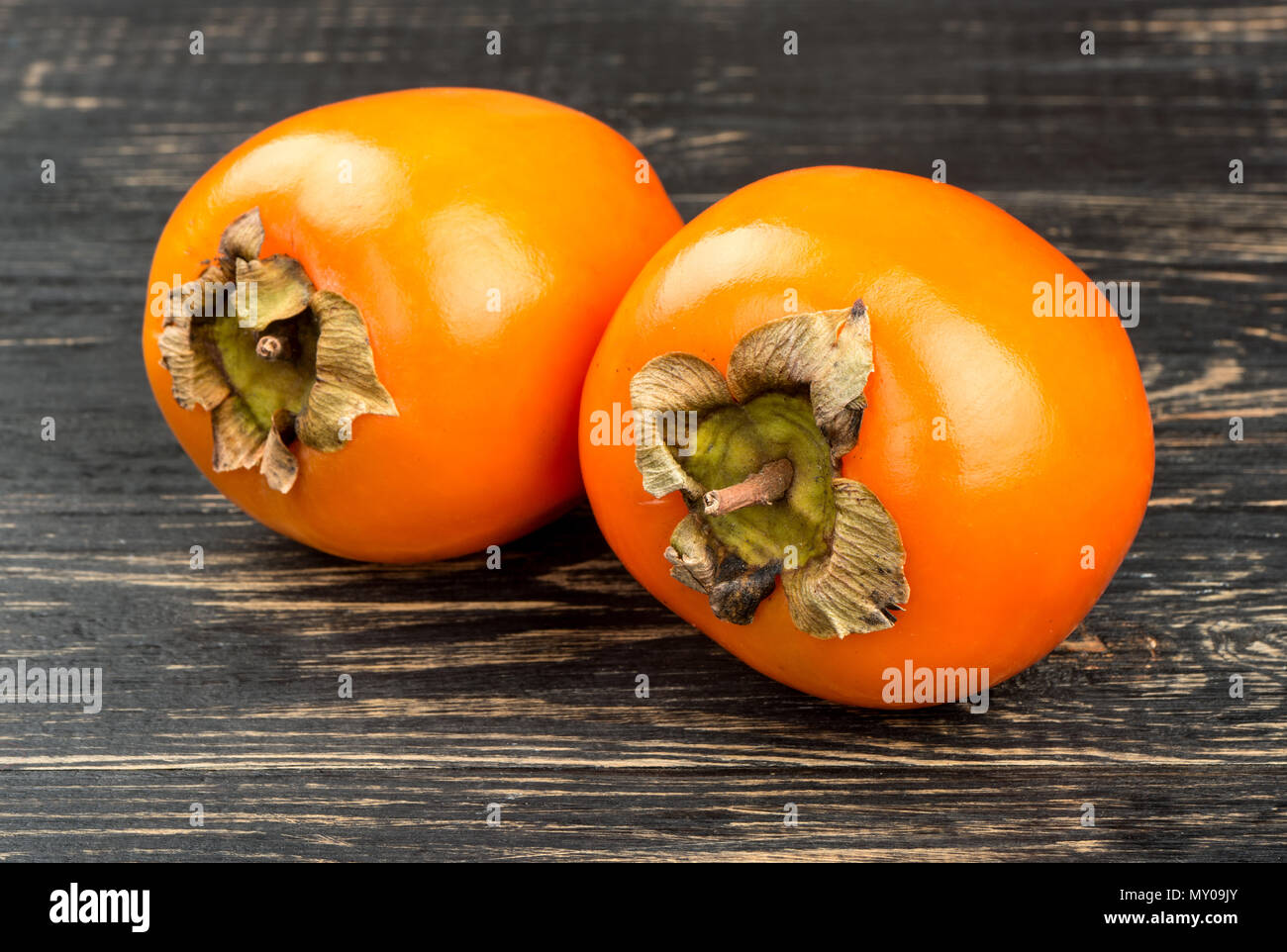 Fruit two ripe persimmons on wooden background closeup Stock Photo