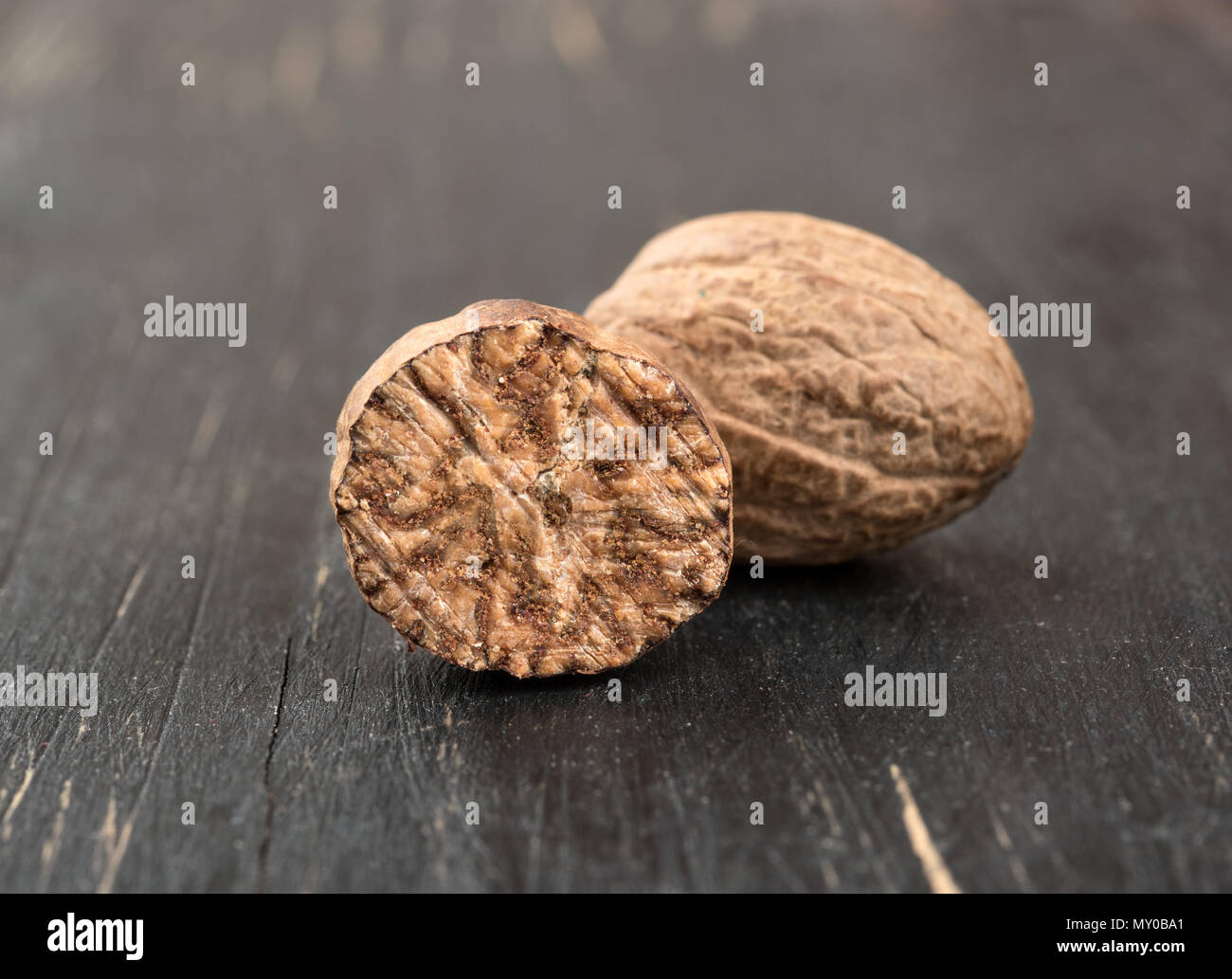 Dry nutmeg with half on wooden background Stock Photo Alamy